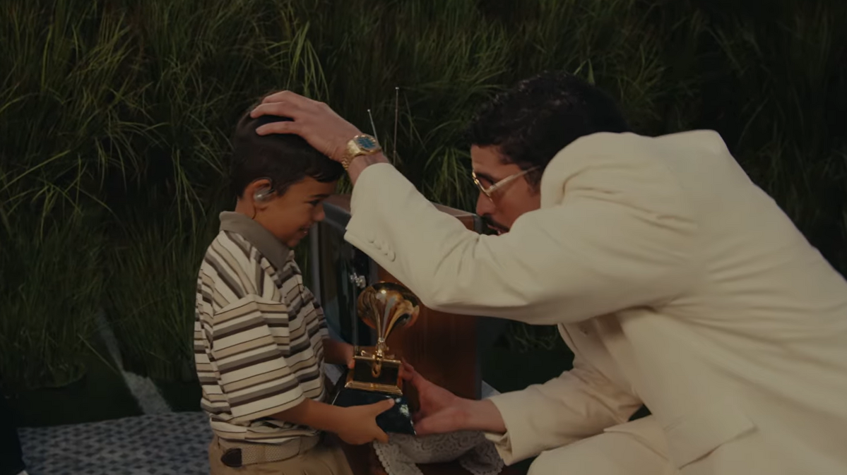 어린아이에게 그래미 트로피를 건네줌으로써 미래 세대의 라틴계 아이들에게 자신의 유산을 이어주고자 하는 의지를 보여준다. / 출처: Bad Bunny's Apple Music Super Bowl Halftime Show