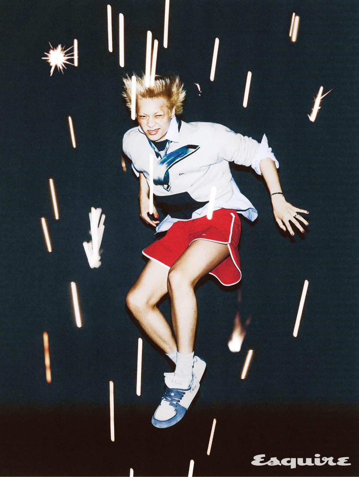그레이 코튼 크루넥 맨 스웨트셔츠, 블루 스트라이프 리넨 캔버스 맨 셔츠, 스트라이프 맨 타이, 레드 테크니컬 캔버스 맨 쇼츠, 디올 로디 레이스업 맨 하이톱 스니커즈 모두 디올.